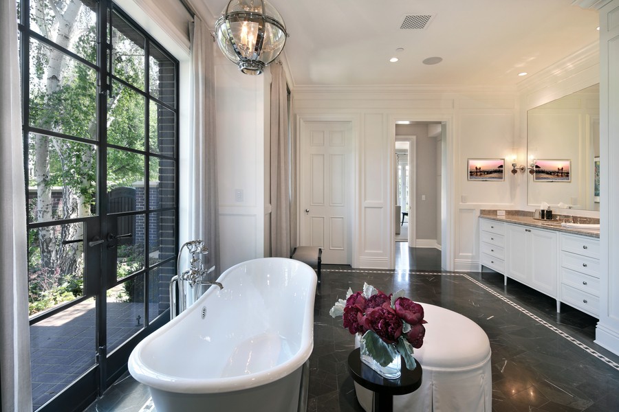 Sonance speakers in a bathroom with a clawfoot tub, flush-mount light fixtures, and white cabinets.