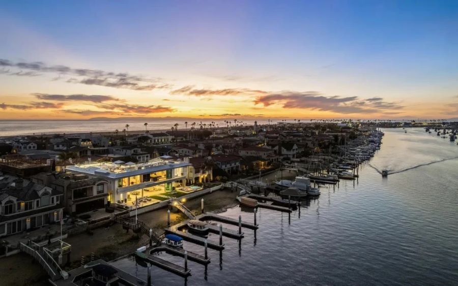 A well-lit home on a bay inlet surrounded by homes with little lighting.