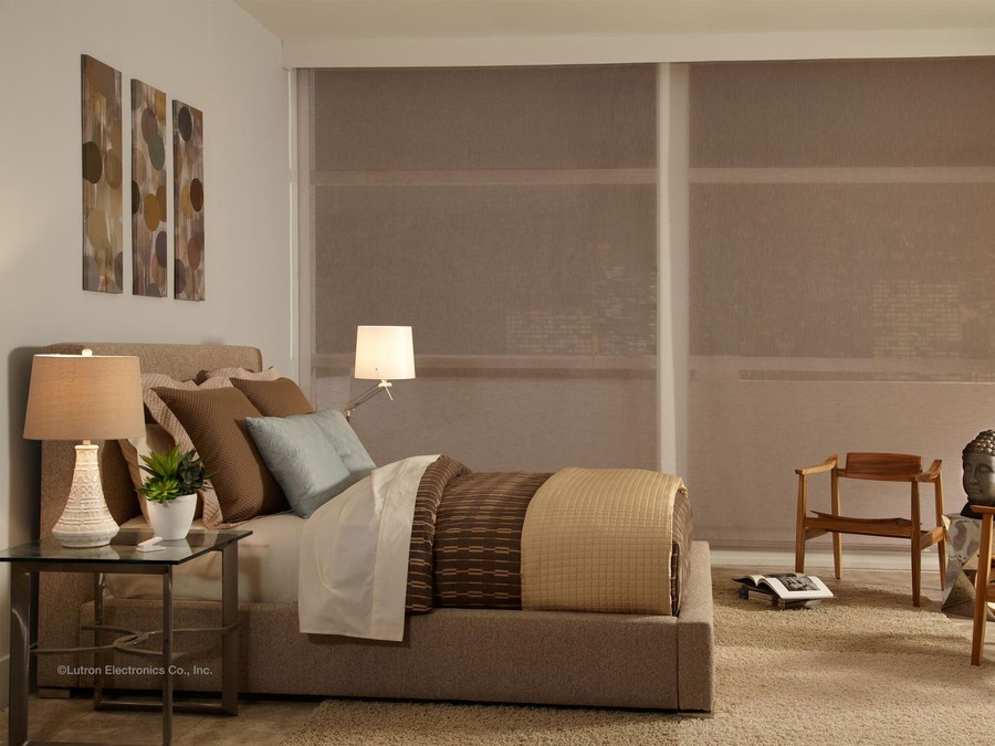 A modern bedroom with brown Lutron shades all the way down.