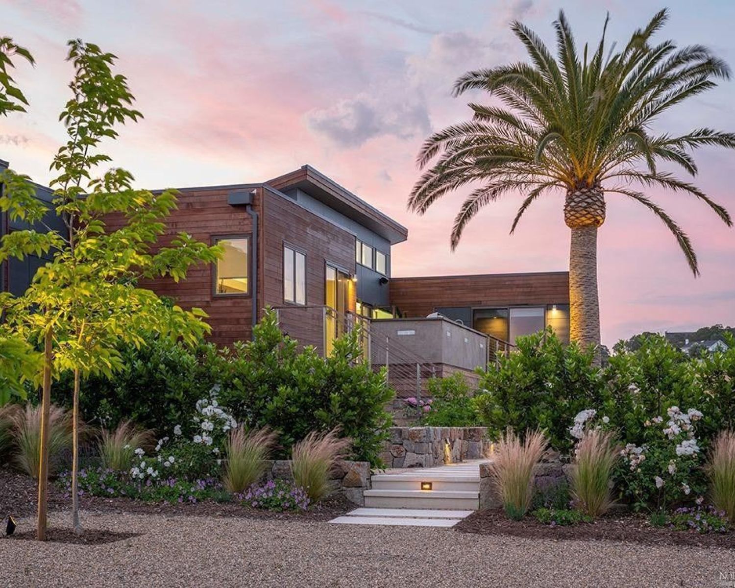 image of modern home at dusk with palm trees and sunset