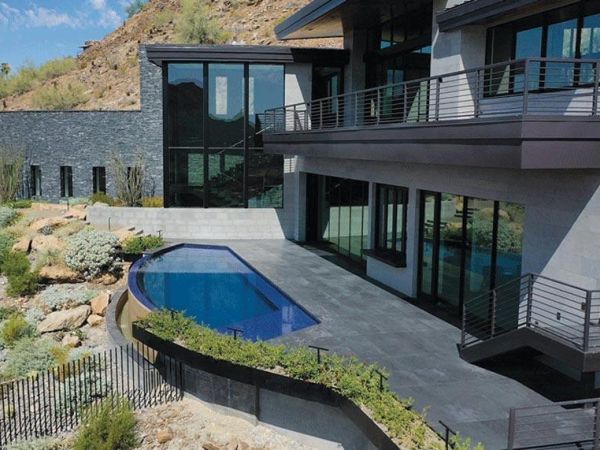 Contemporary hillside home with a sleek pool and spacious patio area, offering stunning views and modern architecture.