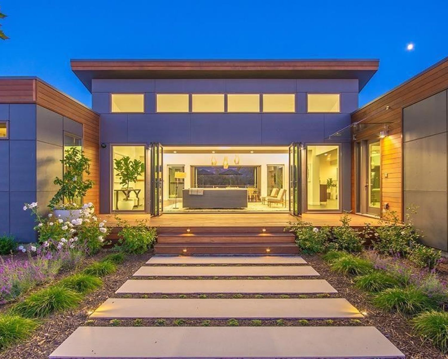 modern home lit up at dusk with glass front